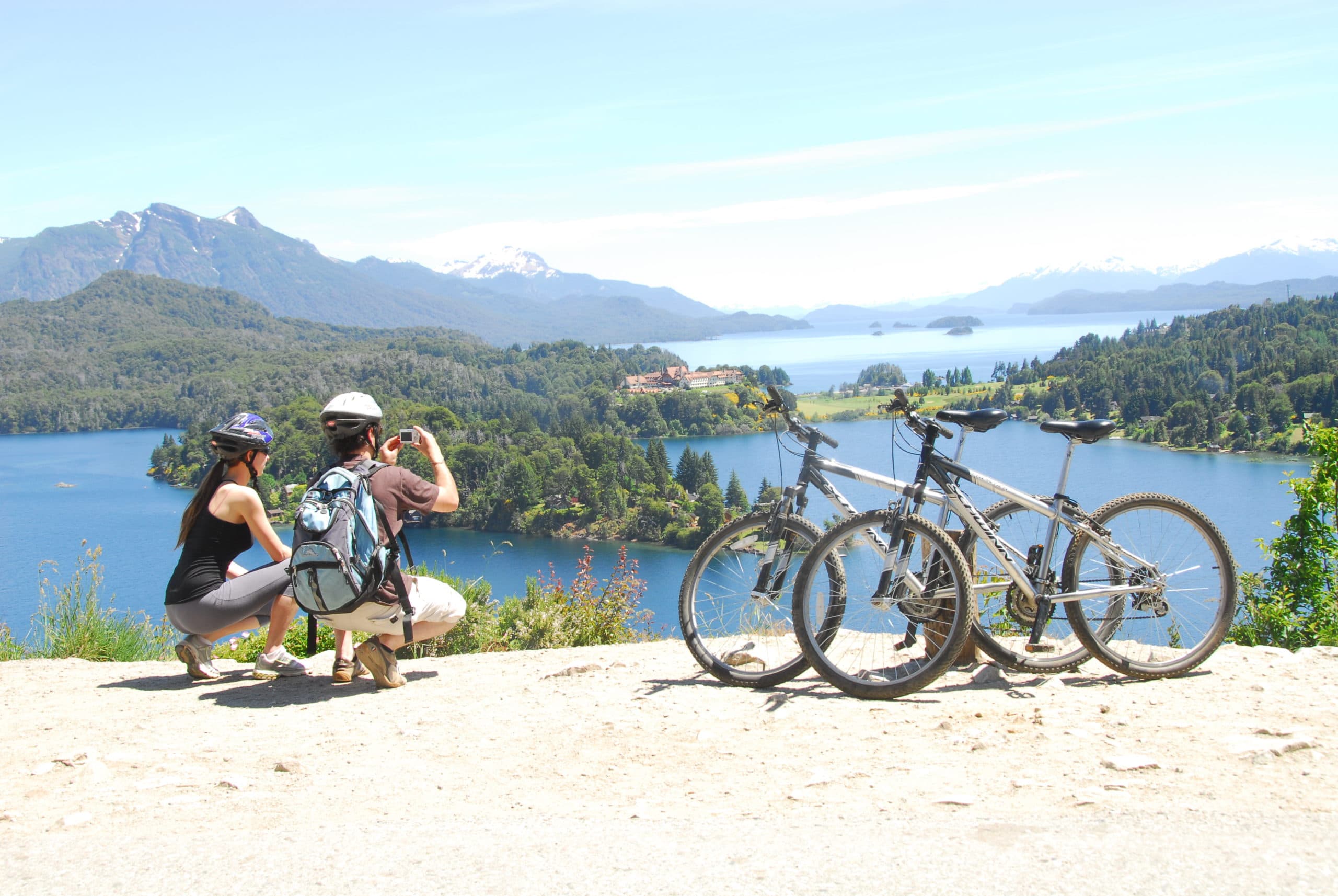 Dos personas con sus bicis frente al lago, en el Circuito Chico de Bariloche.